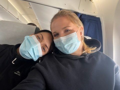 Zwei Personen mit Gesichtsmasken lächeln in die Kamera im Flugzeug.