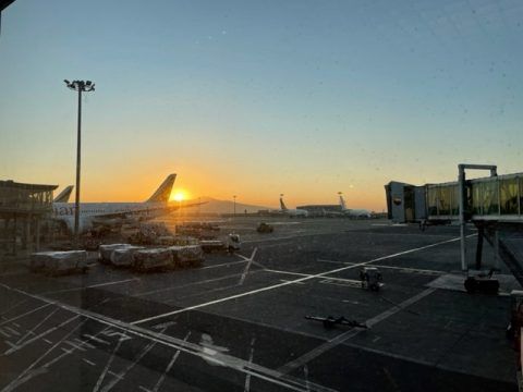 Sonnenuntergang am Flughafen mit Flugzeugen und Bodenfahrzeugen auf dem Vorfeld.