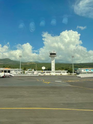 Flugverkehrskontrollturm an einem sonnigen Tag mit blauem Himmel und Wolken, gesehen vom Flughafenvorfeld