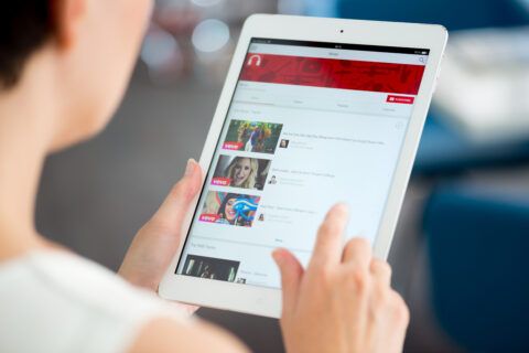 Person betrachtet YouTube-Inhalte auf einem Tablet, symbolisiert digitales Marketing und Social Media Strategien.