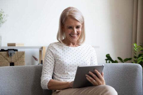 Lächelnde Person betrachtet Tablet, symbolisiert digitales Marketing und SEO-Strategien.